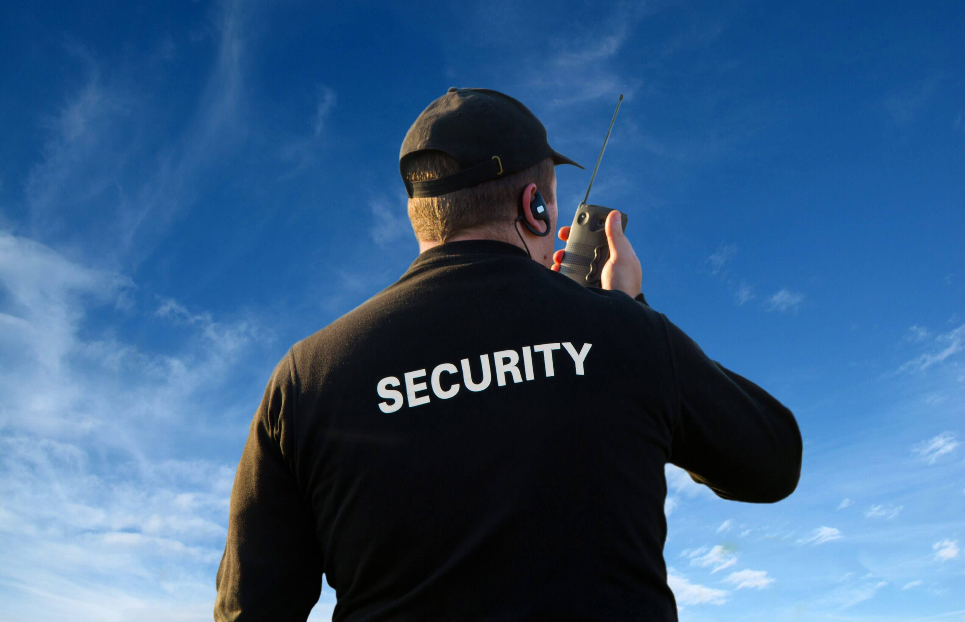 Security guard using radio under blue sky.