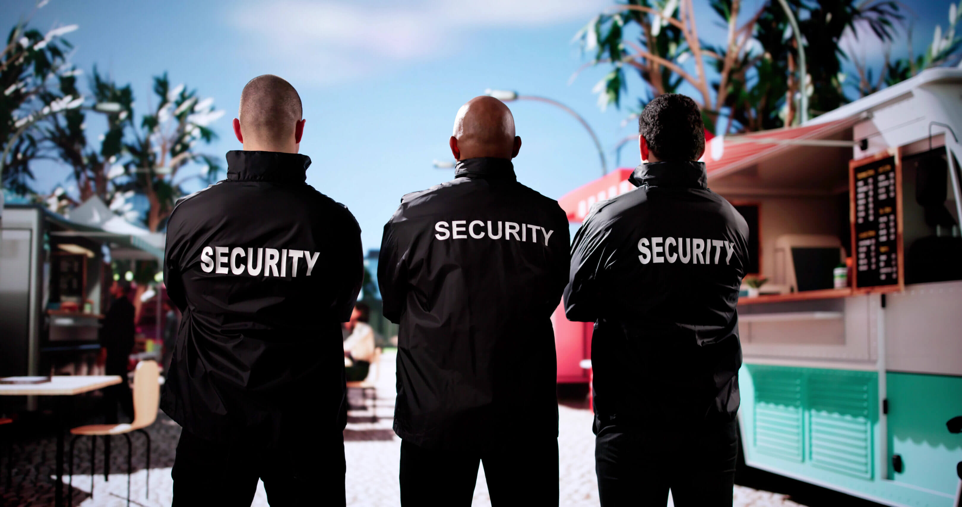 Three security guards standing near food trucks.